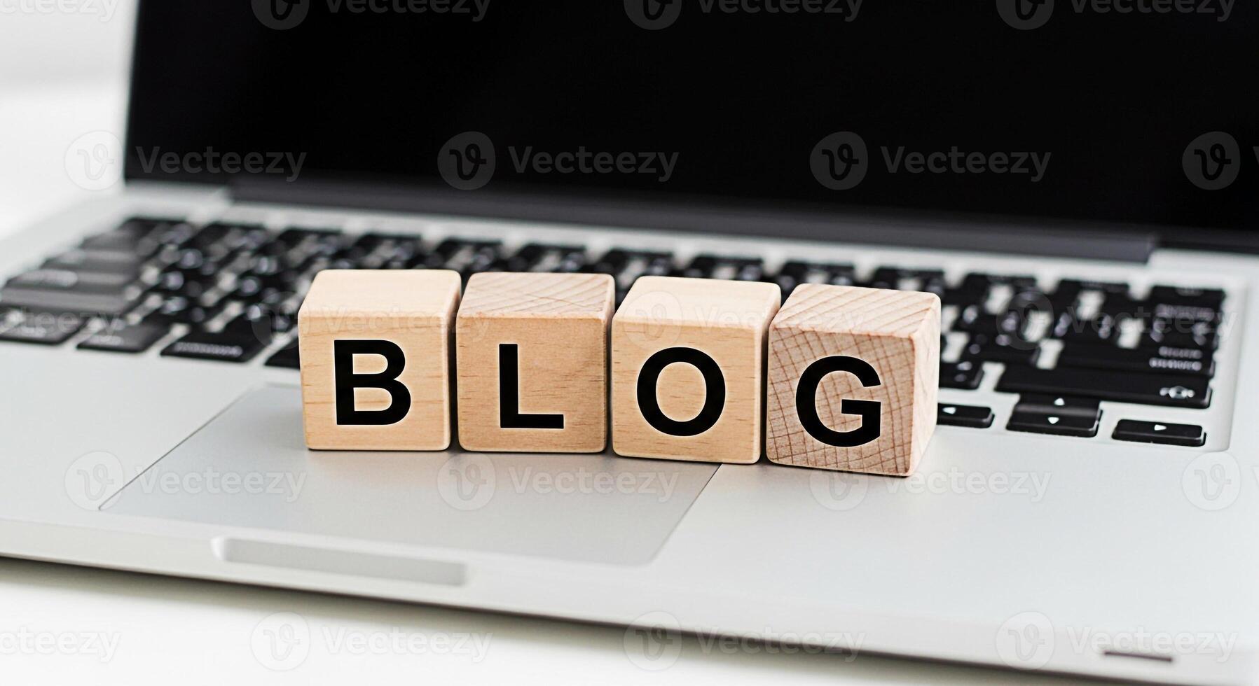 Wooden blocks spelling BLOG resting on a silver laptop keyboard in a bright modern workspace symbolizing online content creation digital marketing and the importance of blogging for business success photo