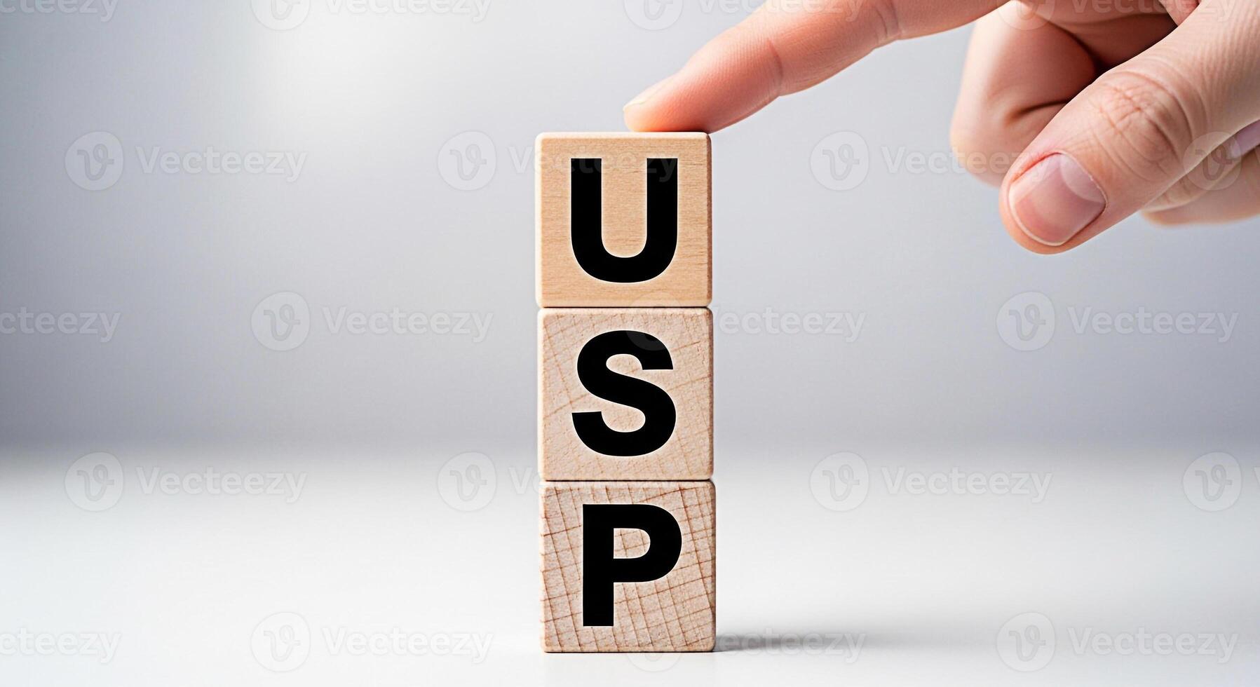 Hand arranging wooden blocks with the letters USP in a bright studio setting symbolizing Unique Selling Proposition and highlighting the importance of differentiation and competitive advantage in busi photo