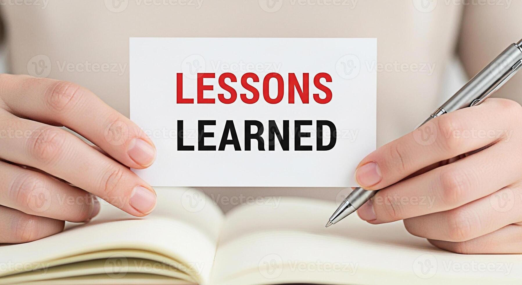 Closeup of hands holding a card with the text Lessons Learned over an open notebook symbolizing reflection and experience in a learning environment fostering a mood of growth and selfimprovement photo