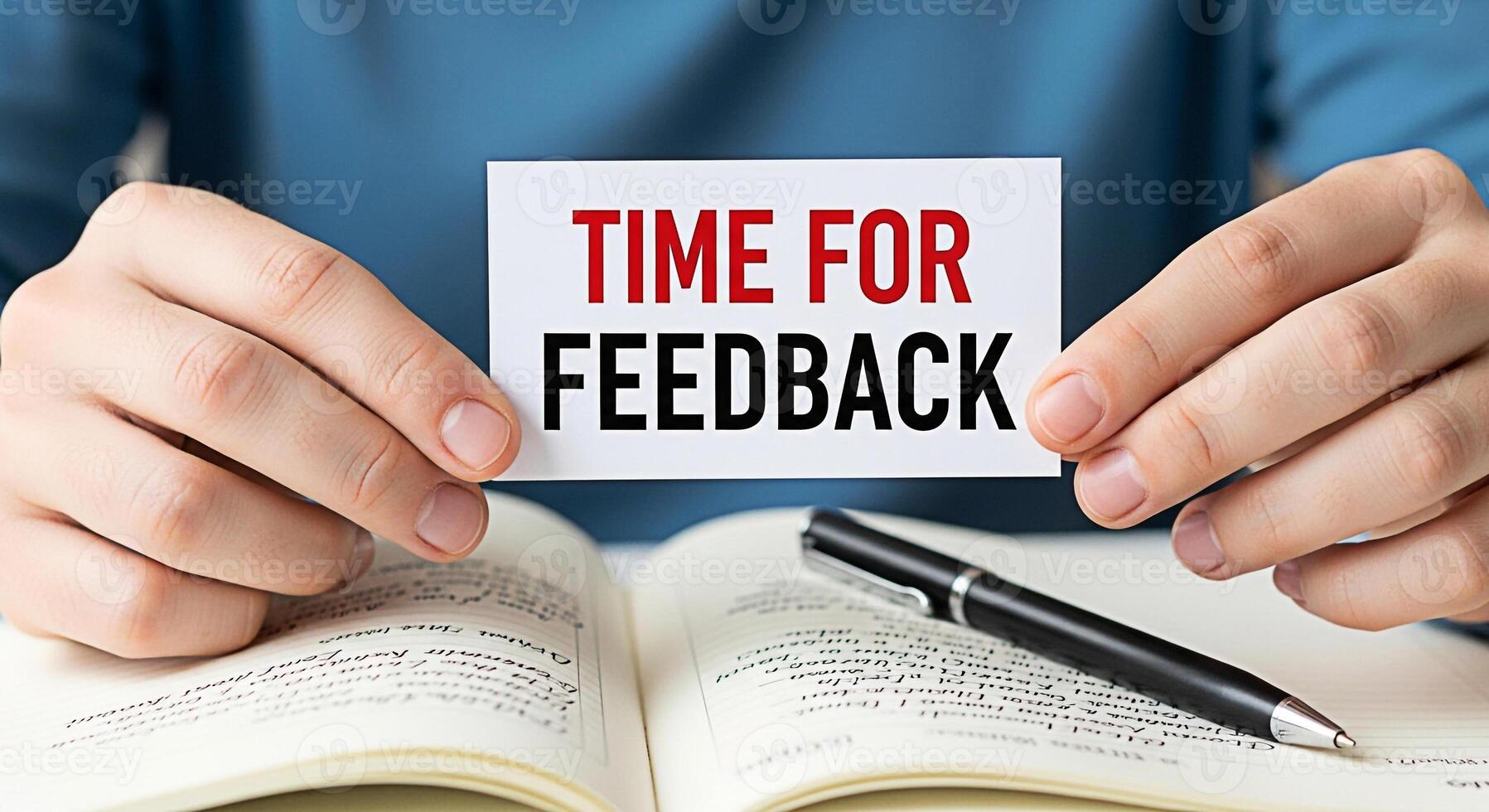 Person holding a card with the words Time for Feedback over an open notebook with a pen suggesting a moment of reflection and evaluation in a learning or professional environment fostering improvement photo