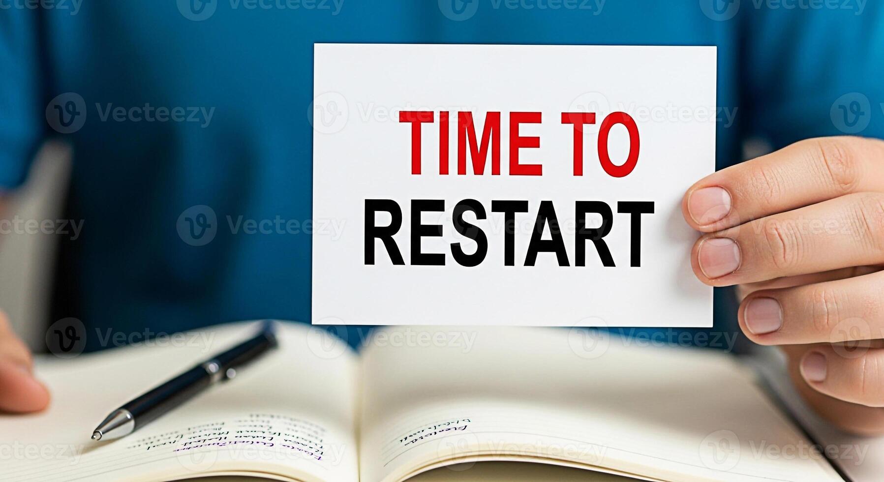 Closeup of a hand holding a card with the words Time to Restart over an open notebook with a pen symbolizing a fresh start new beginnings and the need for change in a business or personal project photo