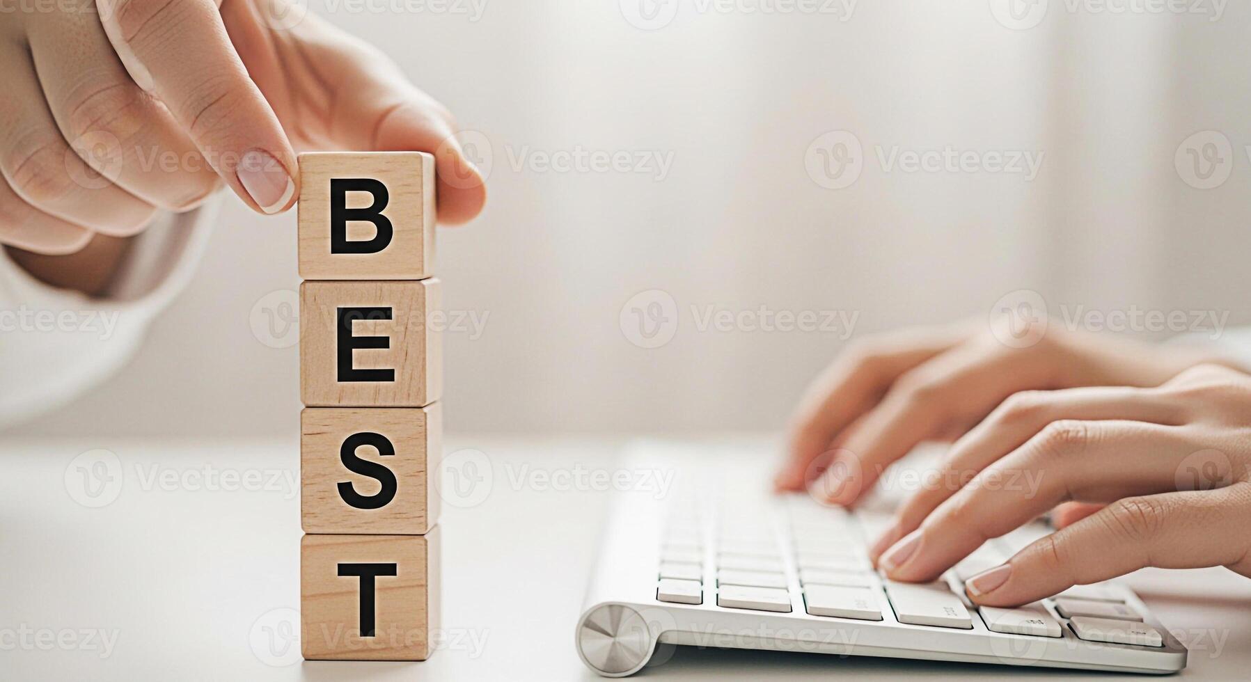 Person stacking wooden blocks spelling BEST while typing on a keyboard in a bright minimalist office setting symbolizing success achievement and striving for excellence in business and personal goals photo