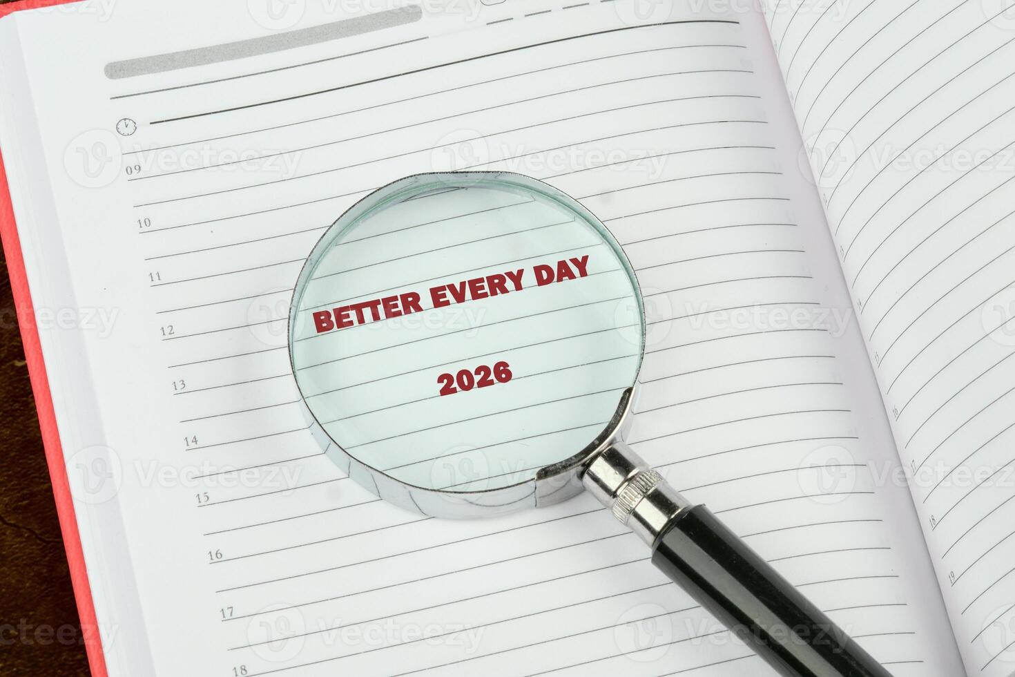 An open planner with Better Every Day and 2026 visible through a magnifying glass suggests planning and focusing on future Success and improvements photo