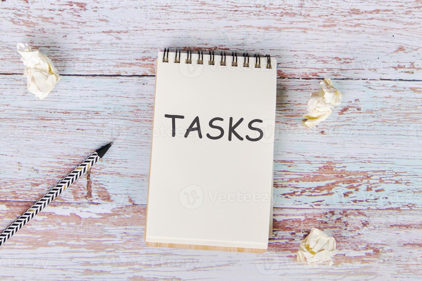 The text of the assignment is written in a notebook lying next to crumpled paper and a pencil photo