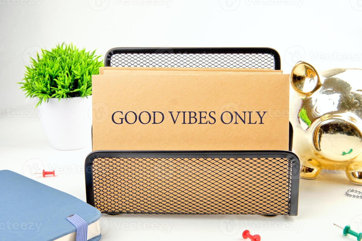 Colorful workspace features a note holder that says good vibes only, surrounded by plants and decorative items, creating an inviting atmosphere for creativity and positivity photo