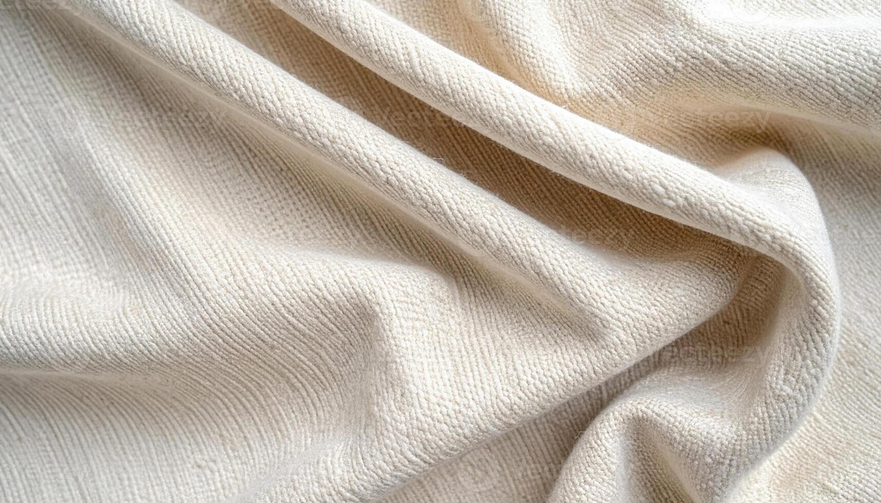 Softly draped cream colored woven fabric cascades in gentle folds creating a textured surface with subtle highlights and shadow details showing. photo
