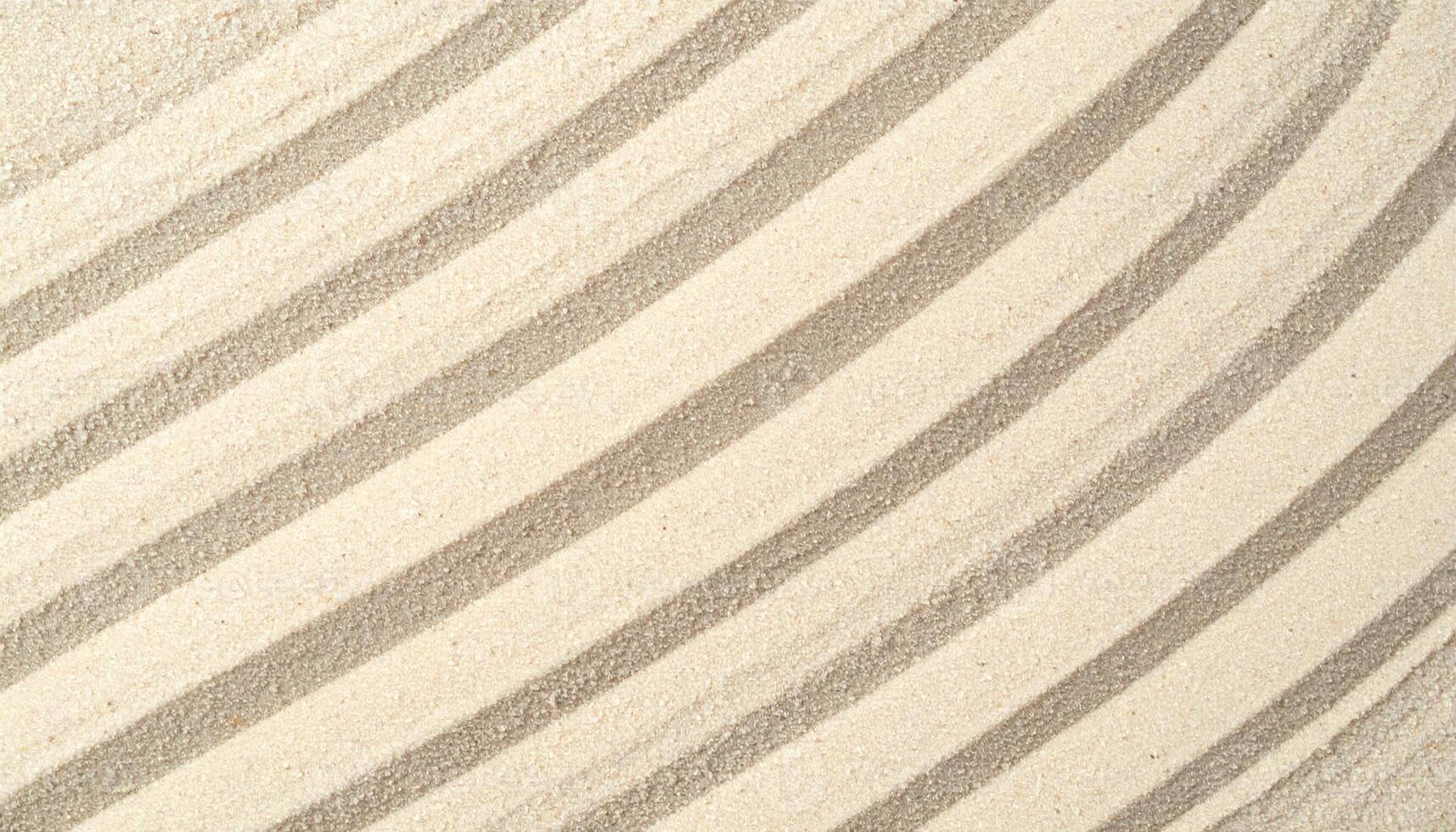 Diagonal patterns and lines are artfully created on the light tan sand surface, exhibiting a minimalist, clean, and textured background. photo