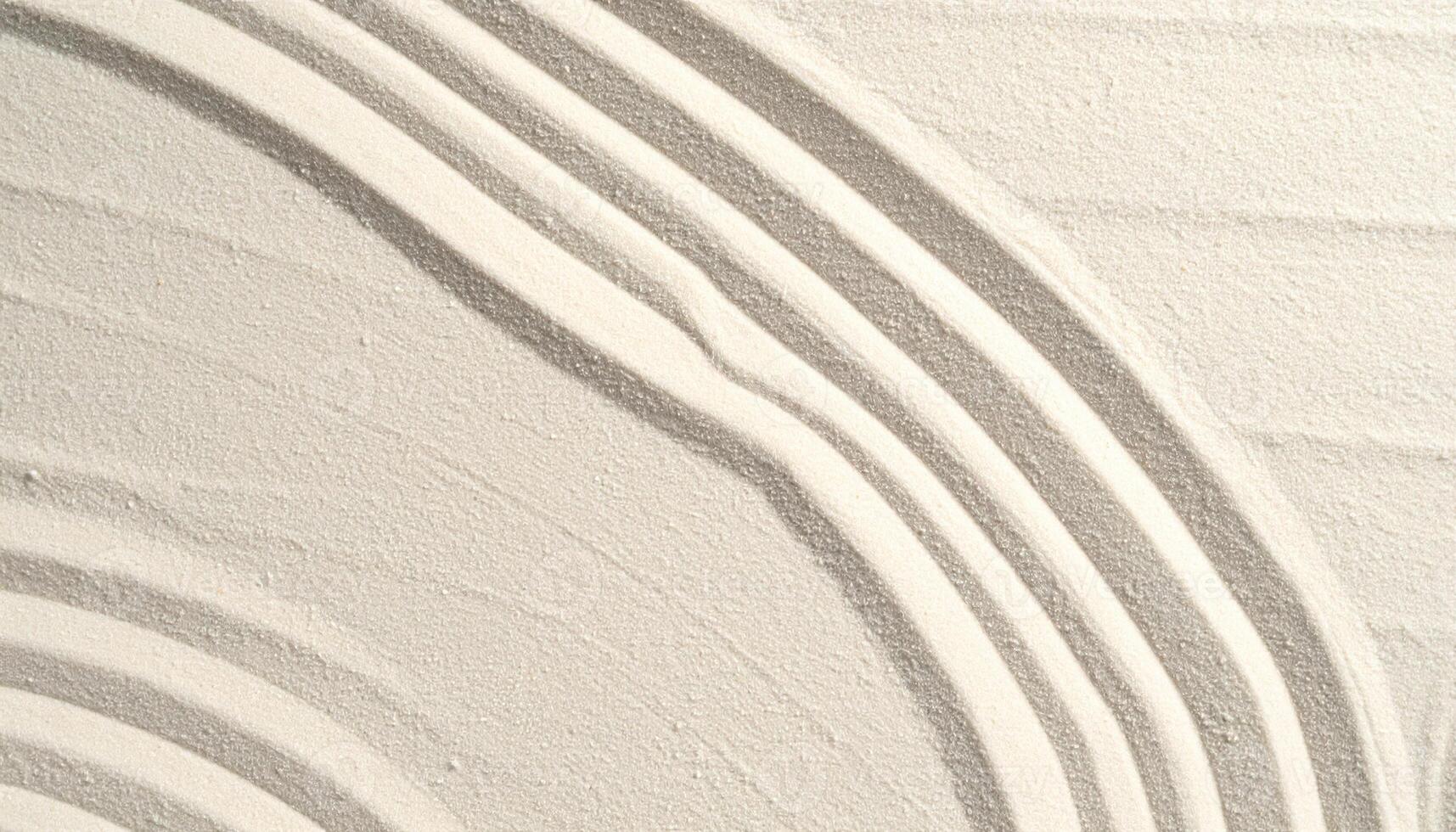 Curved patterns are delicately raked into fine, light colored sand, creating a textured and calming minimalist abstract background design. photo