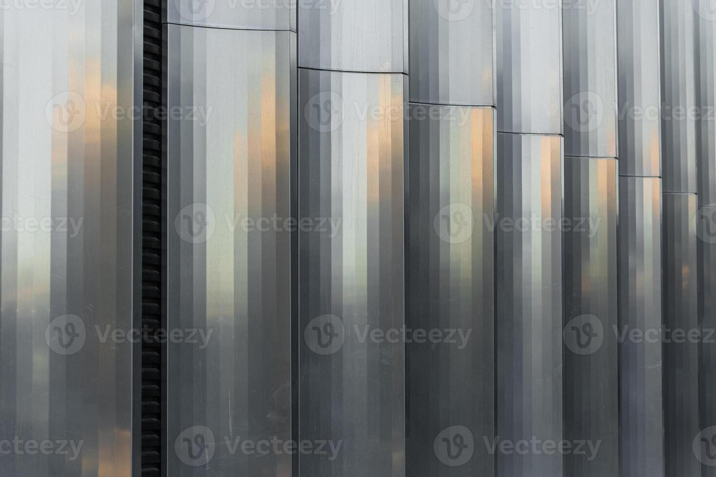 Vertical corrugated metal panels with a reflective surface, create a geometric industrial pattern. Suitable for backgrounds, architecture presentations, and construction industry visuals. photo
