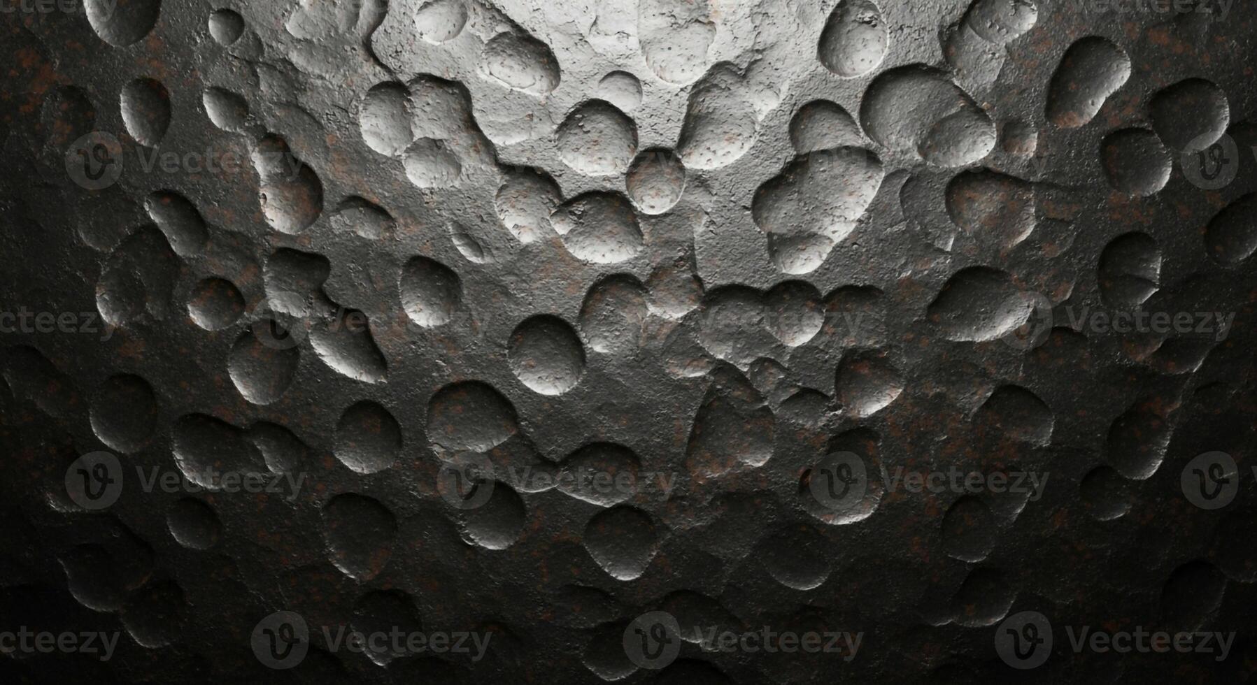 Textured metallic surface with a hammered or dimpled pattern reflecting light and shadow creating depth photo