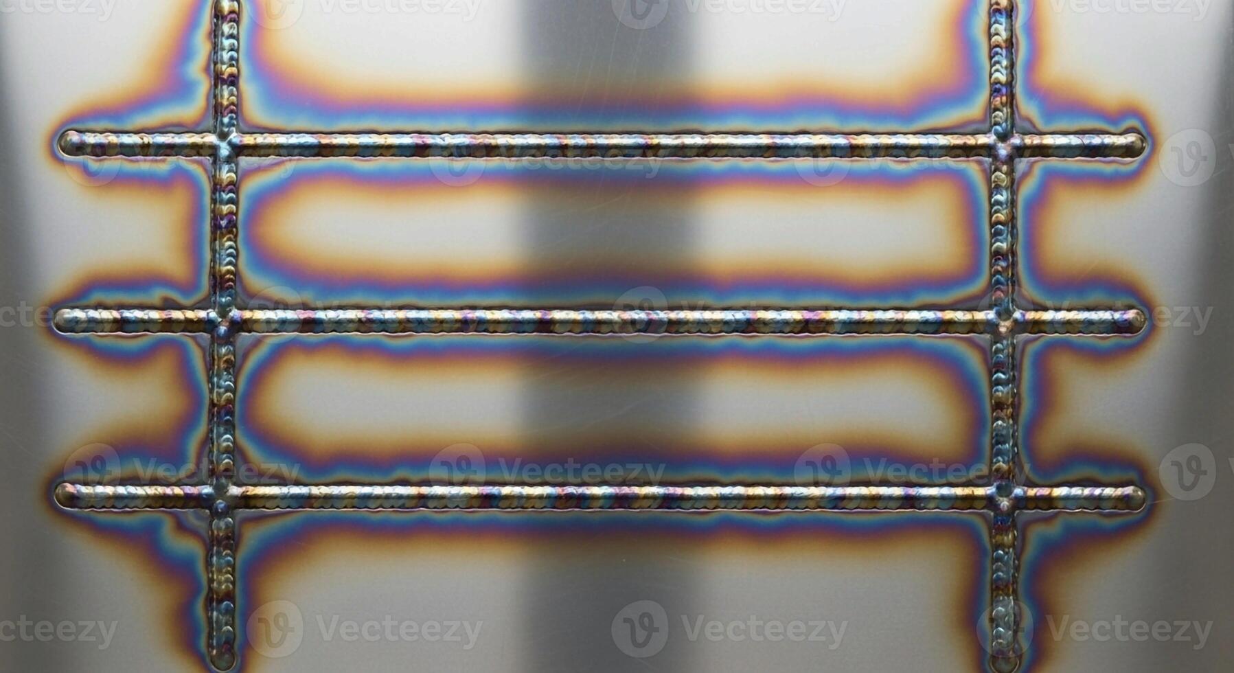 Close up view of a metallic grid structure with heat discoloration showing a rainbow of colors on its surface photo