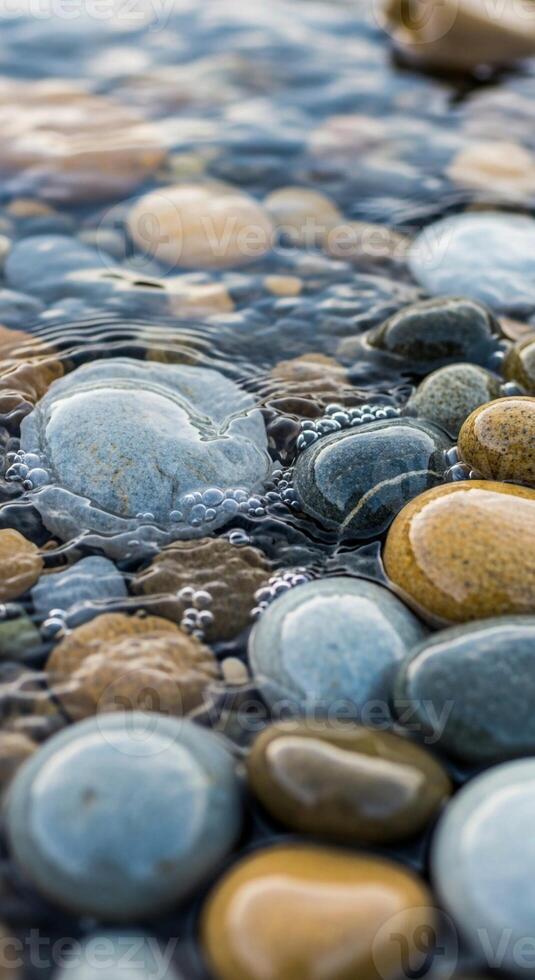Smooth colorful river stones submerged in clear rippling water creating a serene and natural abstract pattern of light and texture photo