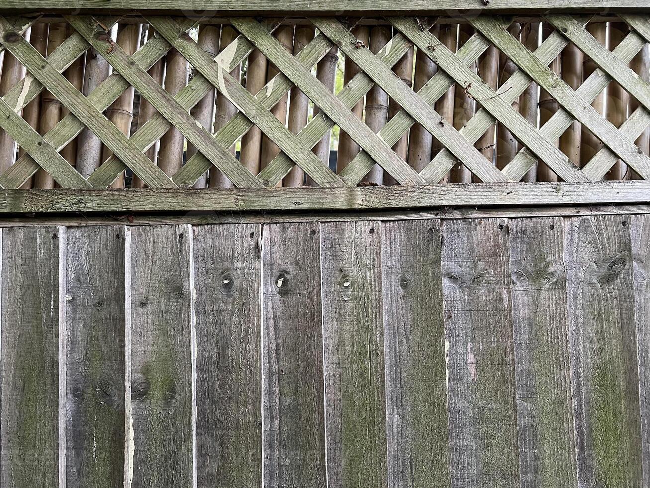 Aged wooden fence with vertical planks and lattice pattern at top. Rough surface with natural grain excellent for background or texture for design, craft, and architectural projects. photo