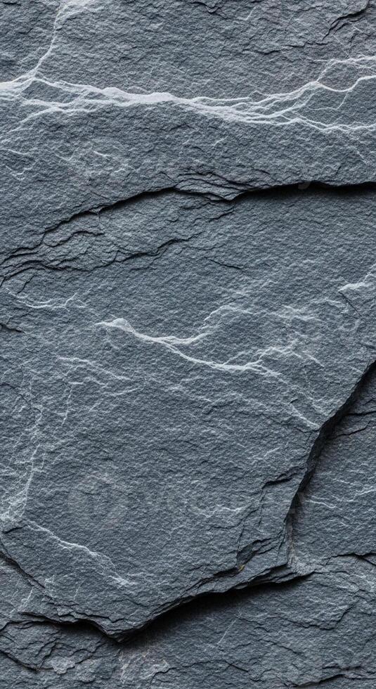 Close up abstract texture of dark grey slate stone with natural layered patterns and subtle light and shadow variations photo