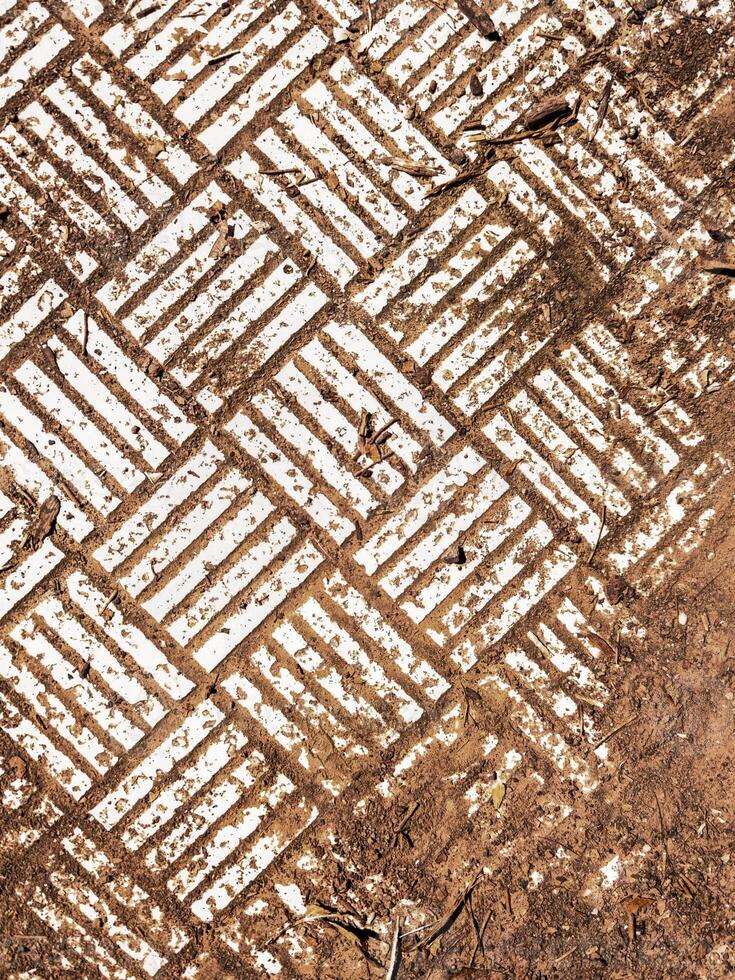 Geometric white pattern on ground texture. Abstract white geometric pattern on earthy textured ground with lines and symmetry. Background for design or texture use. photo