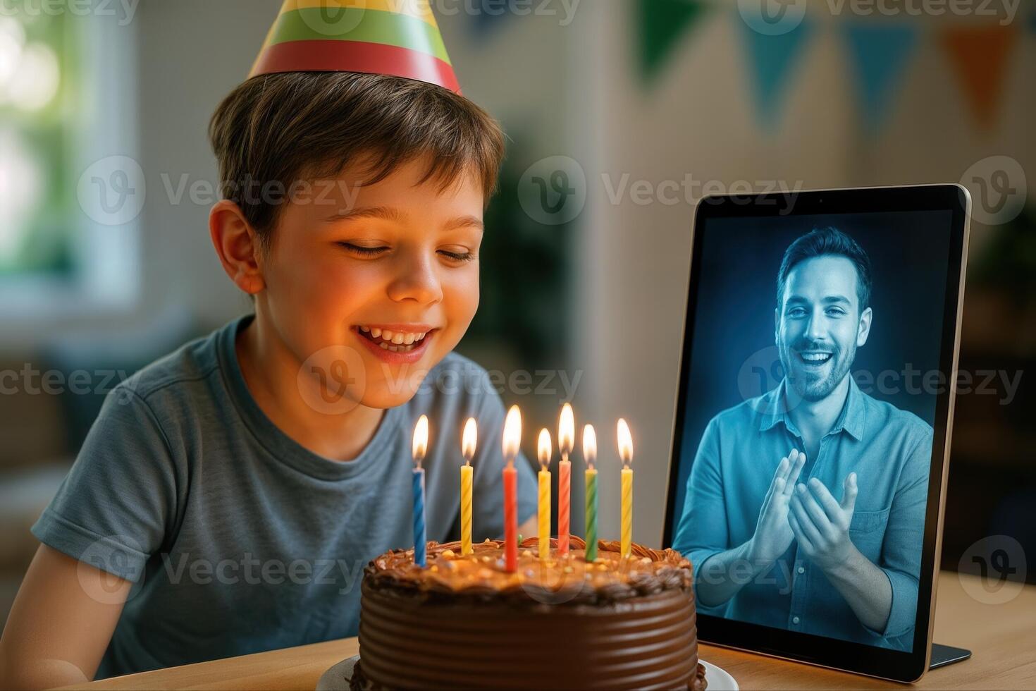 A young boy celebrates his birthday with a chocolate cake, while a holographic image of a man claps from a tablet, creating a virtual party atmosphere photo