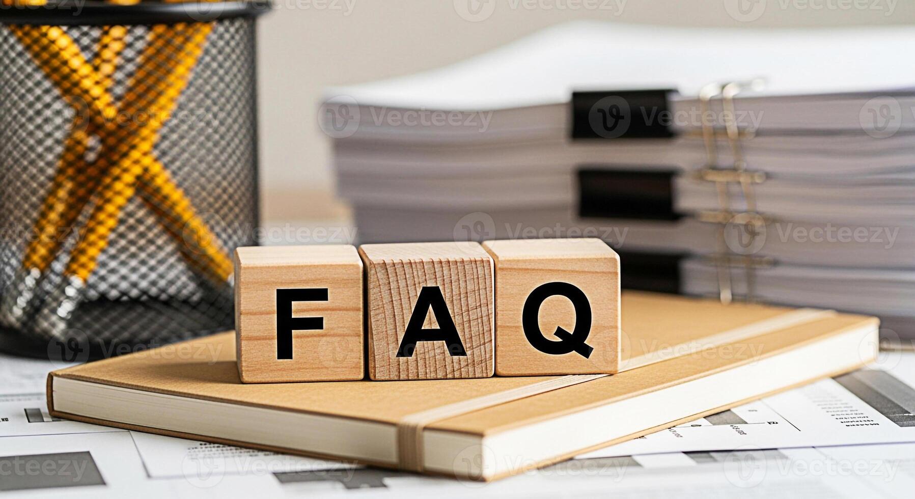 Wooden blocks displaying FAQ on a notebook in a bright office setting representing frequently asked questions customer support and information accessibility for business and online services photo