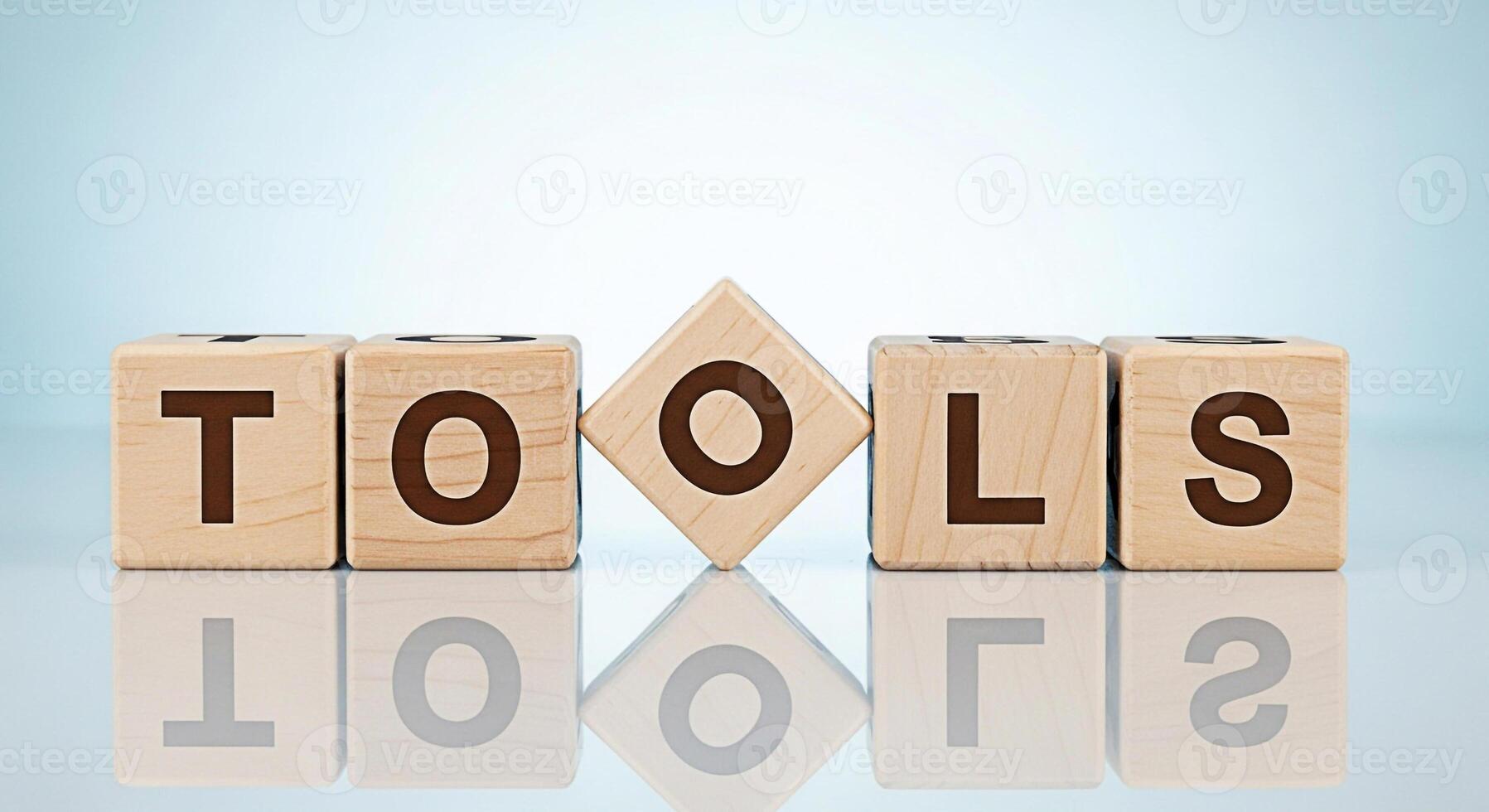Wooden blocks spelling out TOOLS on a reflective surface in a brightly lit studio symbolizing resources skills and equipment needed for success in business and personal development with a clean and mo photo