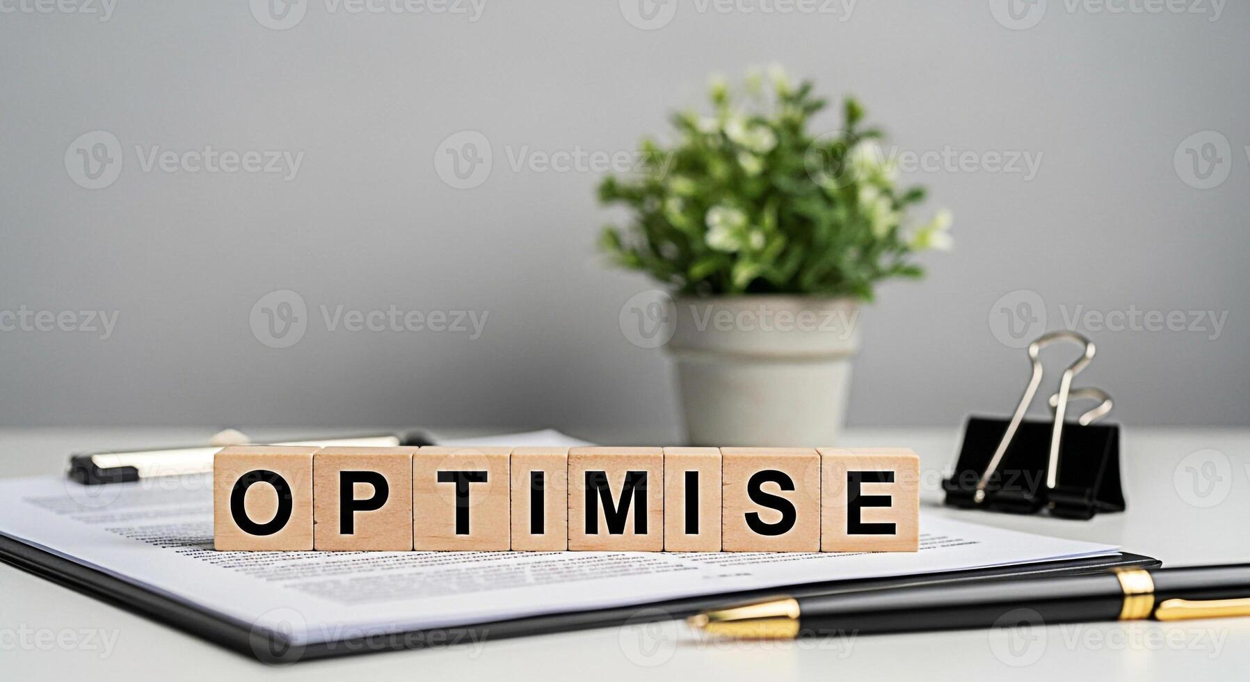Wooden blocks spelling OPTIMISE on a clipboard in a bright office setting symbolizing business growth efficiency and the importance of optimization for achieving success and maximizing potential photo