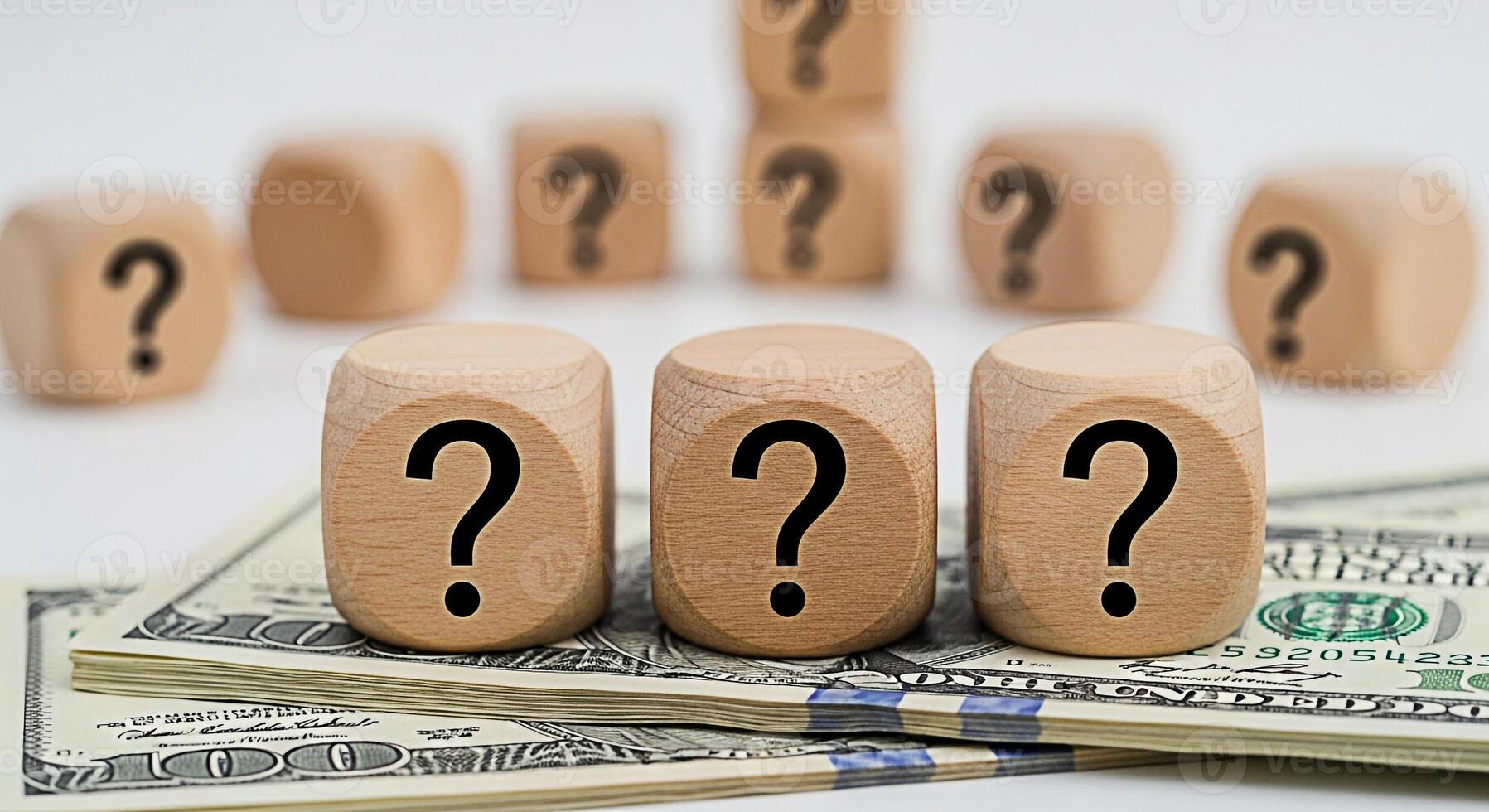Wooden question mark blocks resting on a stack of hundred dollar bills in a bright studio setting representing financial uncertainty investment risks and the search for answers in business and persona photo