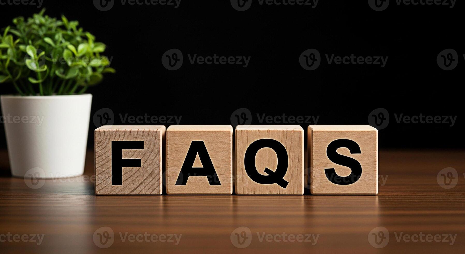 Wooden blocks spelling FAQs on a wooden table with a plant in the background representing frequently asked questions and information resources in a simple and accessible manner photo
