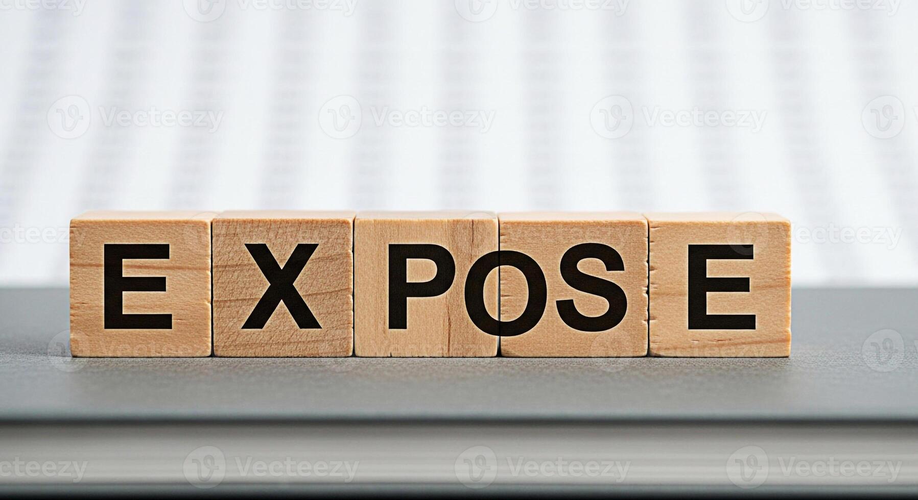 Wooden blocks spelling EXPOSE on a gray surface revealing truth and transparency in a bright minimalist setting symbolizing exposure revelation and uncovering hidden information photo