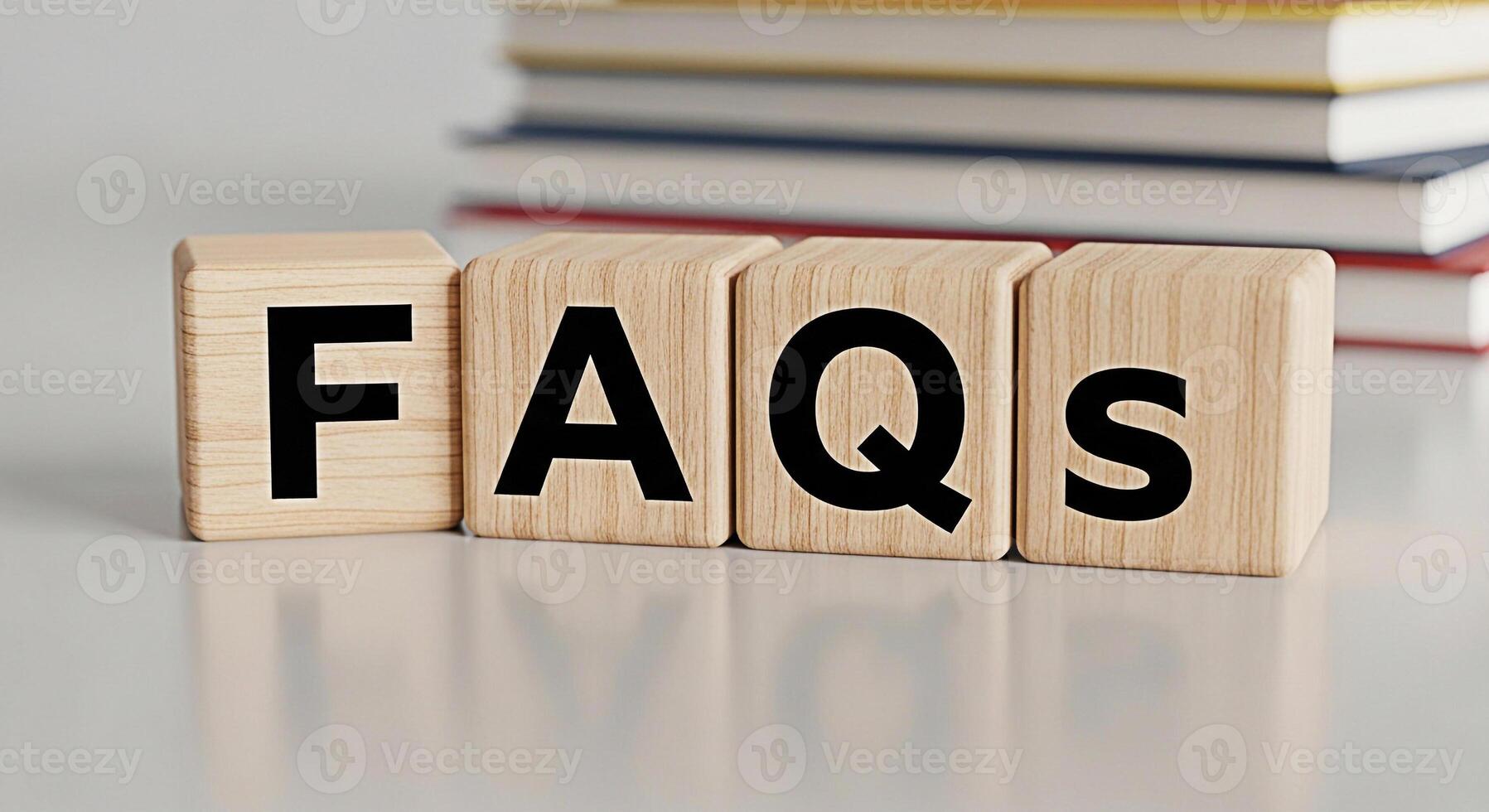 Wooden blocks displaying FAQs on a white table with blurred books in the background representing information assistance and customer support in a clean and modern setting conveying clarity and helpful photo