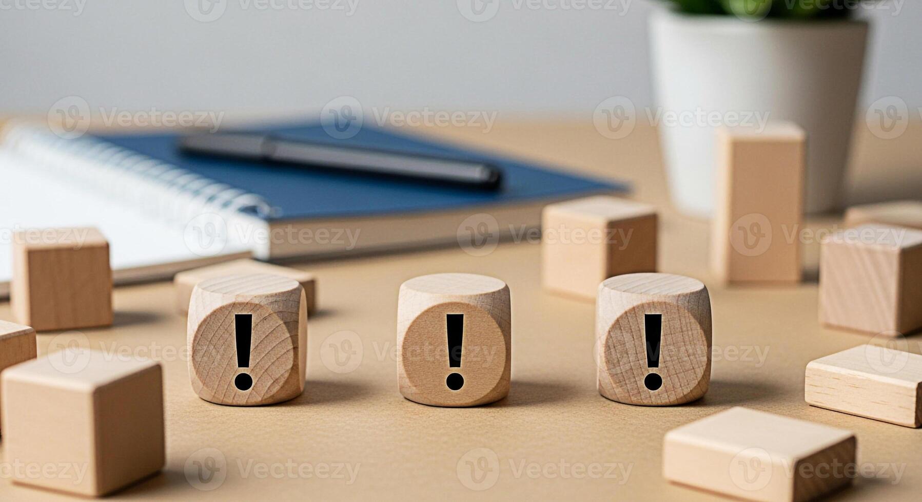 Wooden blocks displaying exclamation marks on a desk with a notebook and pen symbolizing urgent tasks and important reminders in a modern office environment creating a sense of focus and attention to photo