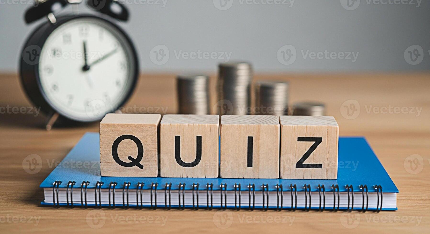 Wooden blocks spelling Quiz resting on a blue notebook with an alarm clock and stacks of coins in the background symbolizing knowledge assessment and financial literacy in a learning environment photo