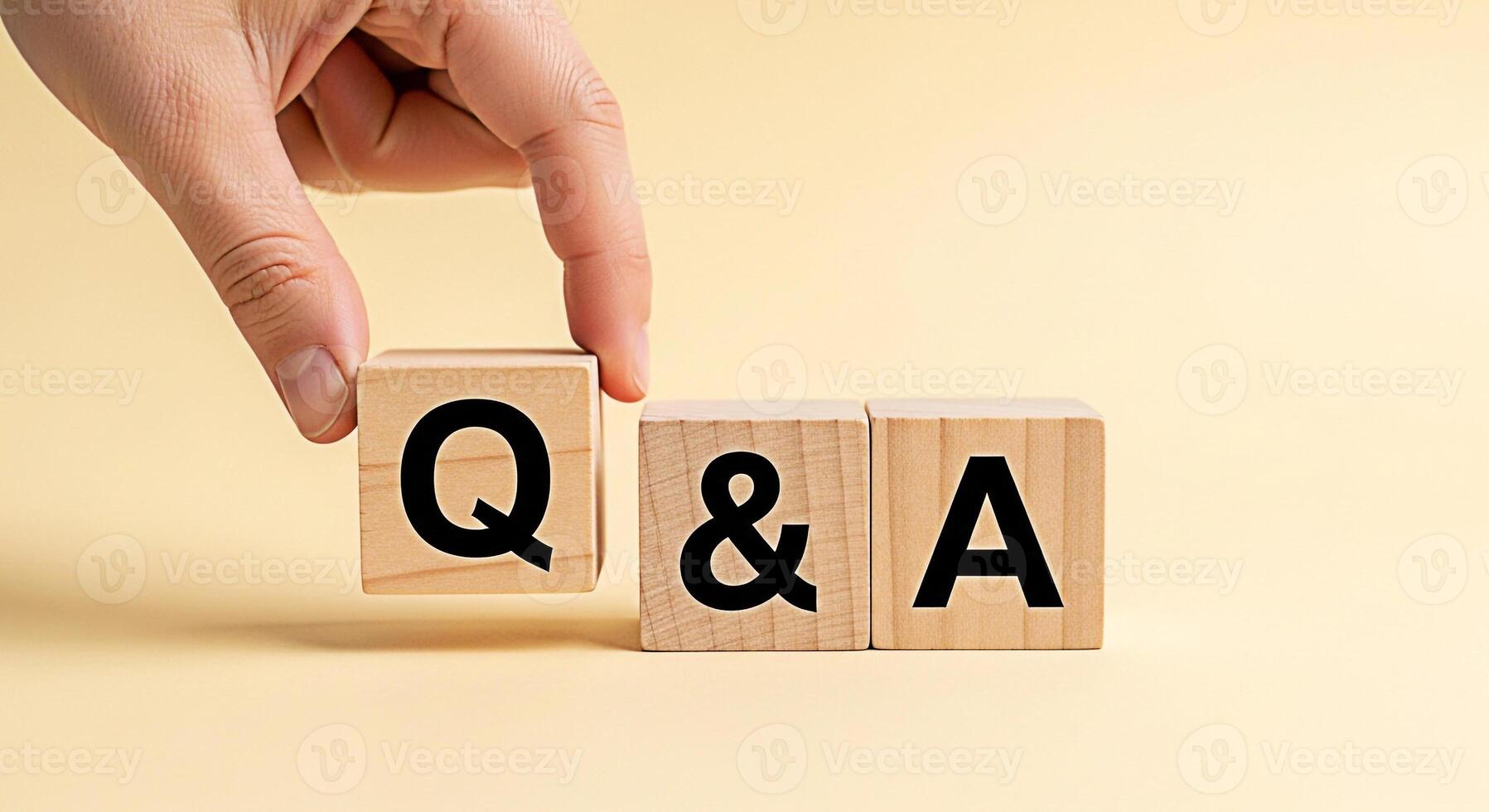 Hand arranging wooden blocks with Q A on a light yellow background representing questions and answers knowledge sharing and interactive communication in a simple and clean studio setting photo