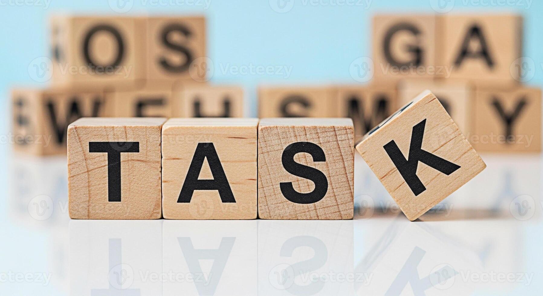 Wooden blocks spelling TASK on a reflective surface with a focus on completing assignments and achieving goals in a bright organized environment conveying a sense of focus and productivity photo