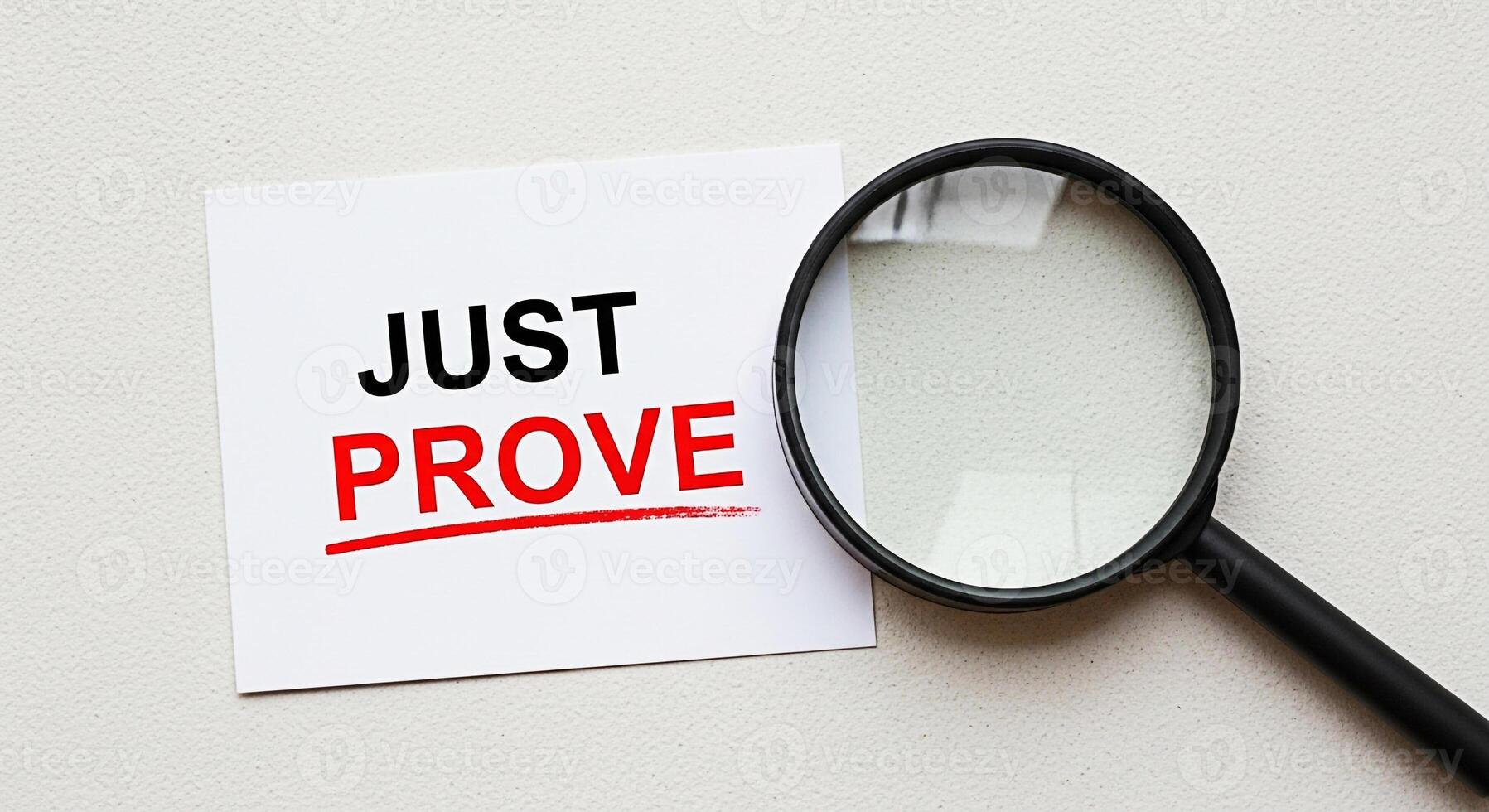 Magnifying glass examining a card with the words Just Prove on a textured surface emphasizing the need for evidence and verification in a business and legal context creating a mood of scrutiny and inv photo