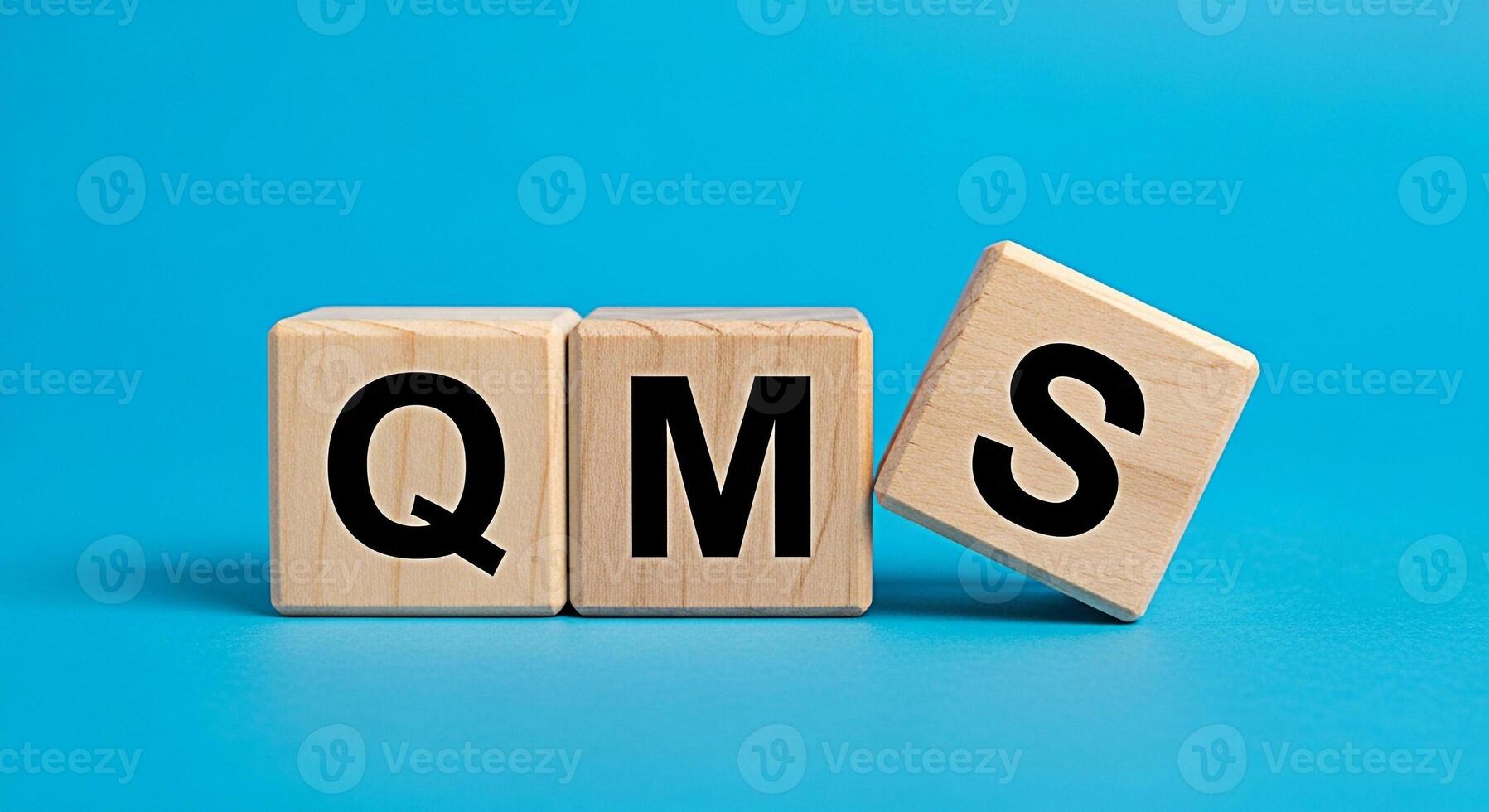Wooden blocks displaying QMS on a vibrant blue background representing Quality Management System implementation and improvement conveying a sense of structure and systematic approach to quality assura photo