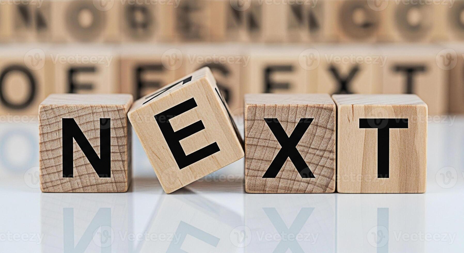 Wooden blocks spelling NEXT on a reflective surface symbolizing forward movement and progress in a business environment creating a positive and motivational atmosphere for future opportunities and gro photo