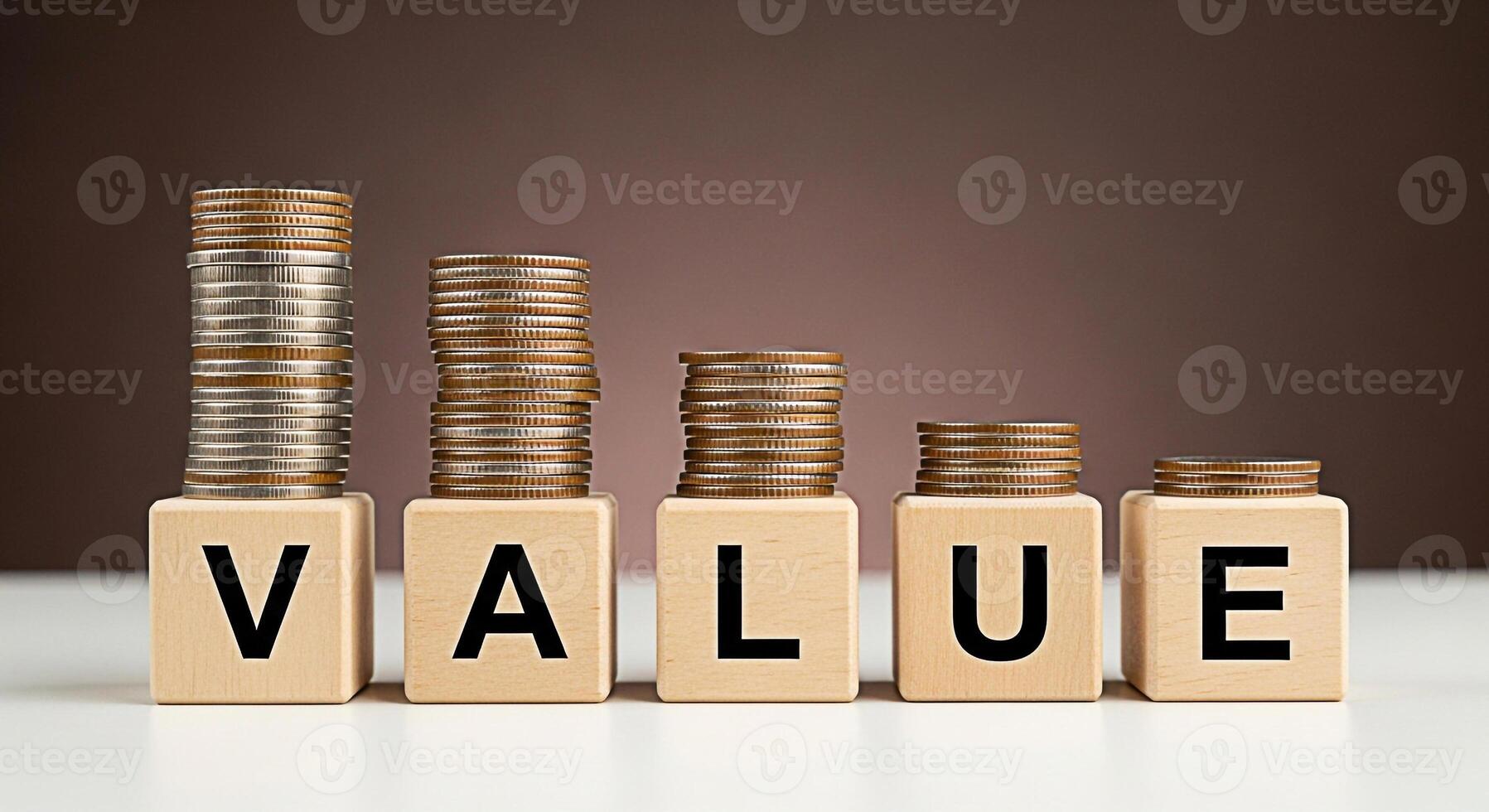 Stacks of coins decreasing in height on wooden blocks spelling VALUE in a studio setting representing financial loss investment risk and the erosion of value in a challenging economic climate photo