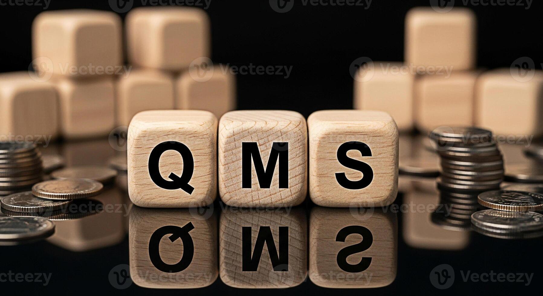 Wooden blocks displaying QMS on a reflective surface with stacked coins and blurred background representing quality management system implementation and financial implications for business success and photo