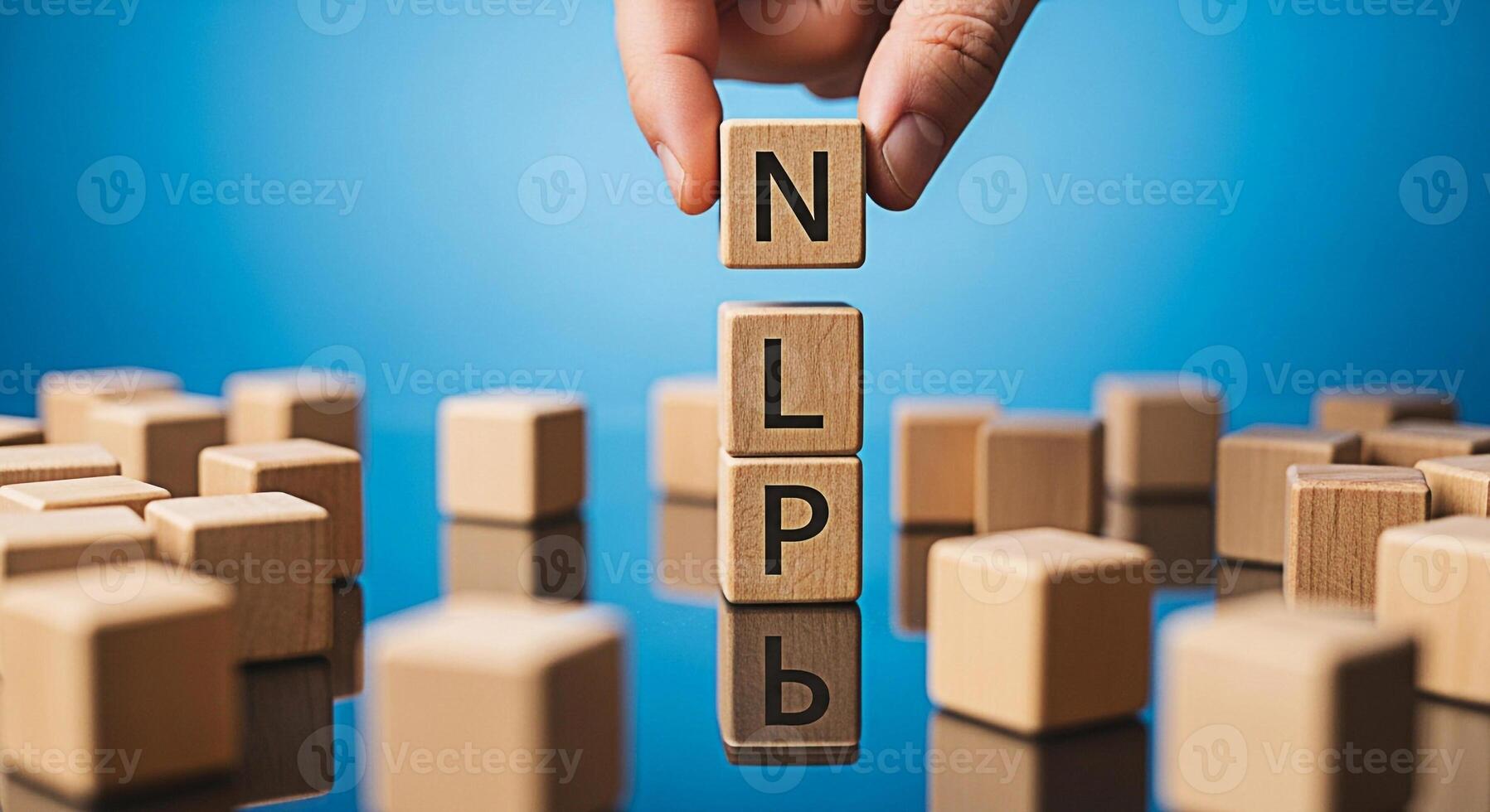Hand placing wooden blocks spelling NLP on a reflective surface against a blue background representing Neuro Linguistic Programming and the power of communication for personal development and success photo
