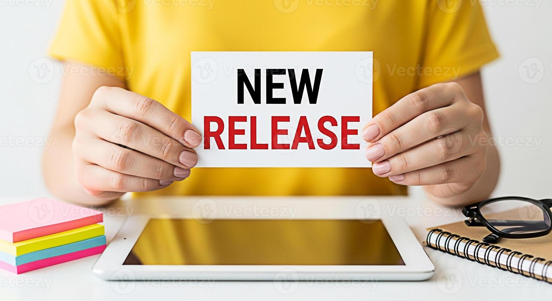 Woman holding a New Release card at her desk surrounded by a tablet sticky notes and notebook creating a vibrant and organized workspace symbolizing productivity and innovation photo