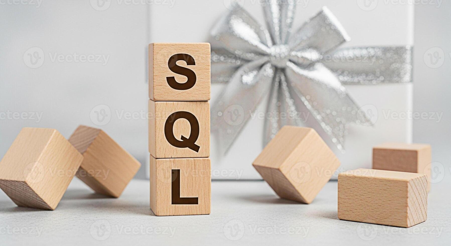 Wooden blocks spelling SQL displayed near a wrapped gift with a silver bow representing database management and structured query language in a clean modern setting conveying a message of data solution photo