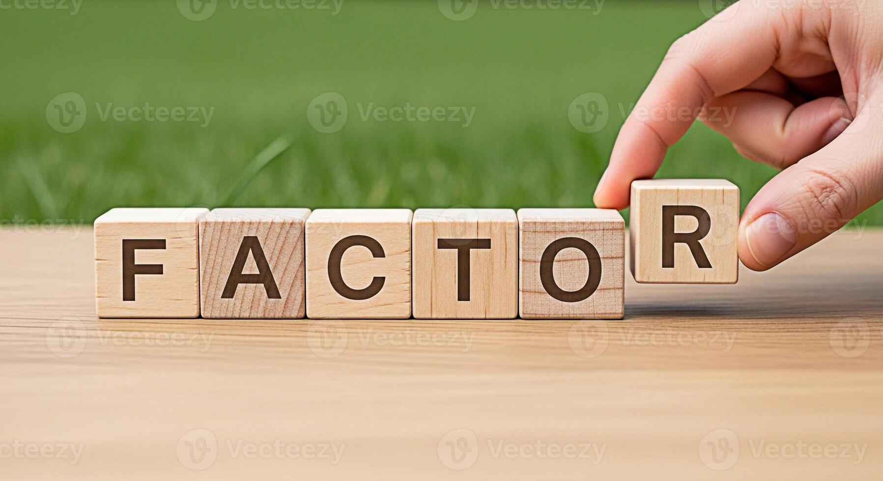 Hand completing the word FACTOR with wooden blocks on a wooden surface in a natural outdoor setting symbolizing influence and key elements for success and decisionmaking conveying a sense of importanc photo