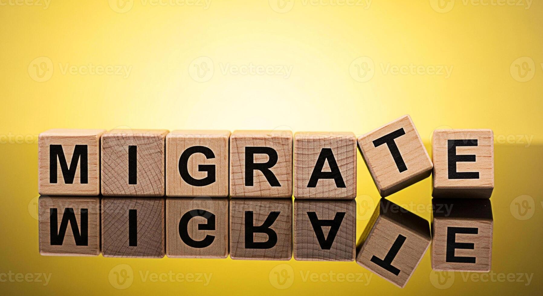 Wooden blocks spelling MIGRATE on a reflective surface against a bright yellow background symbolizing transition relocation and the concept of moving to a new place with a sense of hope and opportunit photo