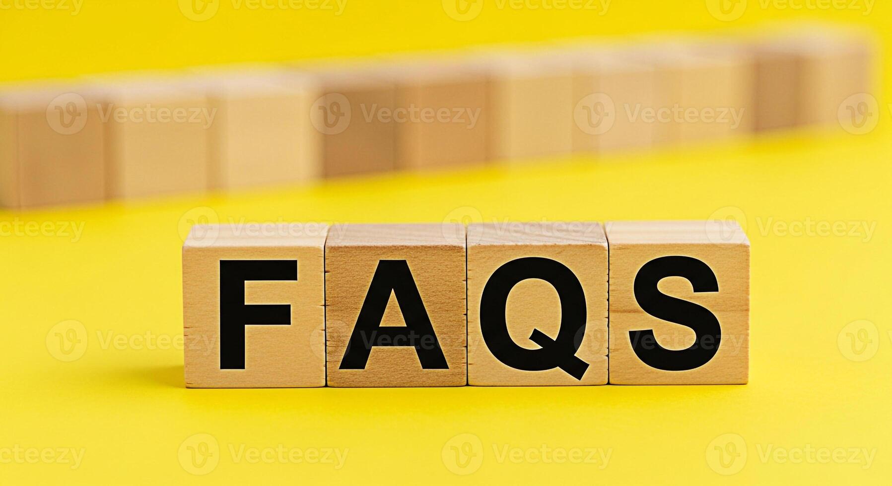 Wooden blocks displaying FAQs on a bright yellow background representing frequently asked questions and providing information creating a clear and helpful concept for customer support and online assis photo