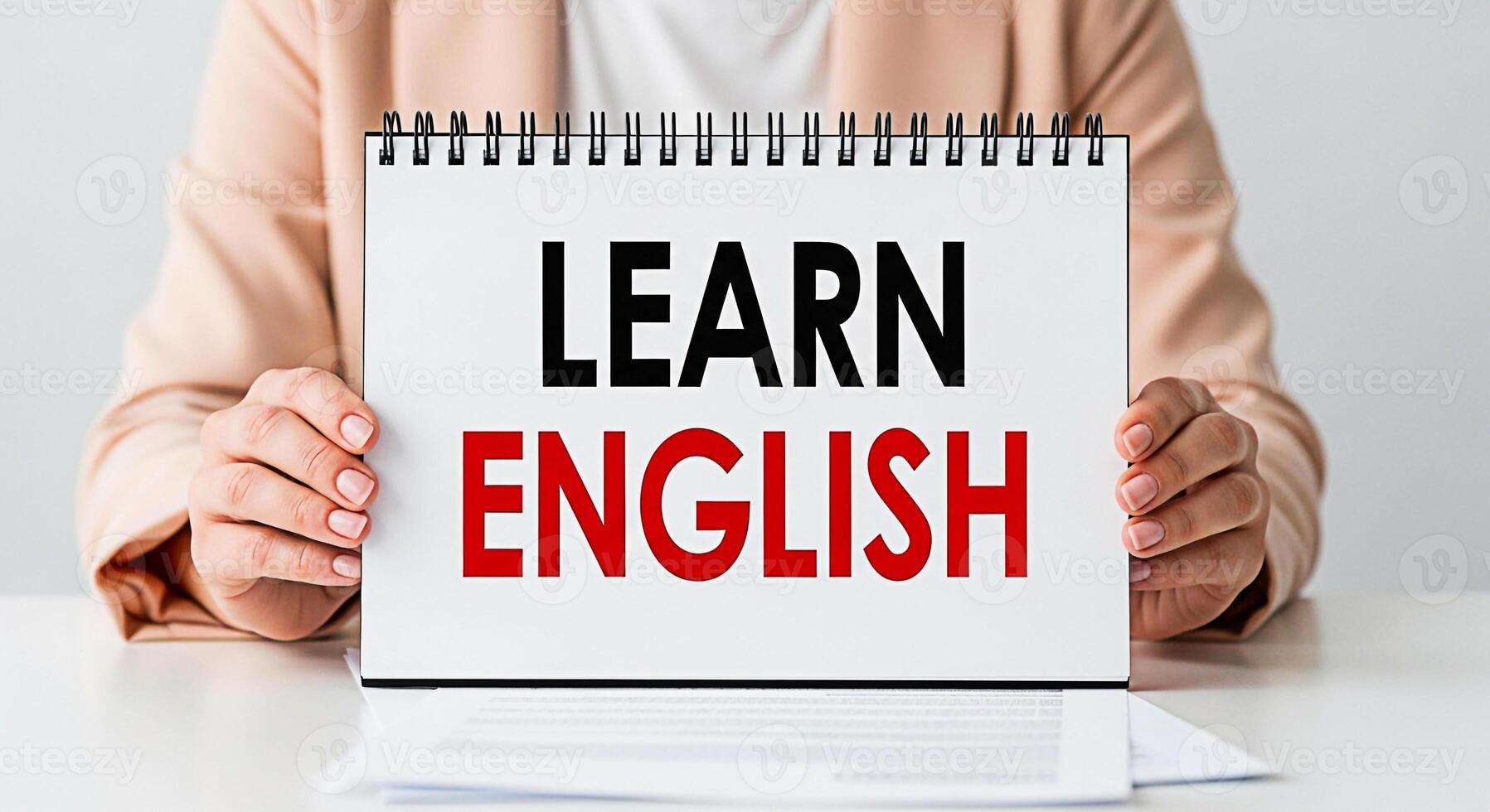 Woman in a peach blazer holding a notepad with the words Learn English in a bright minimalist studio setting conveying a message of education and selfimprovement photo