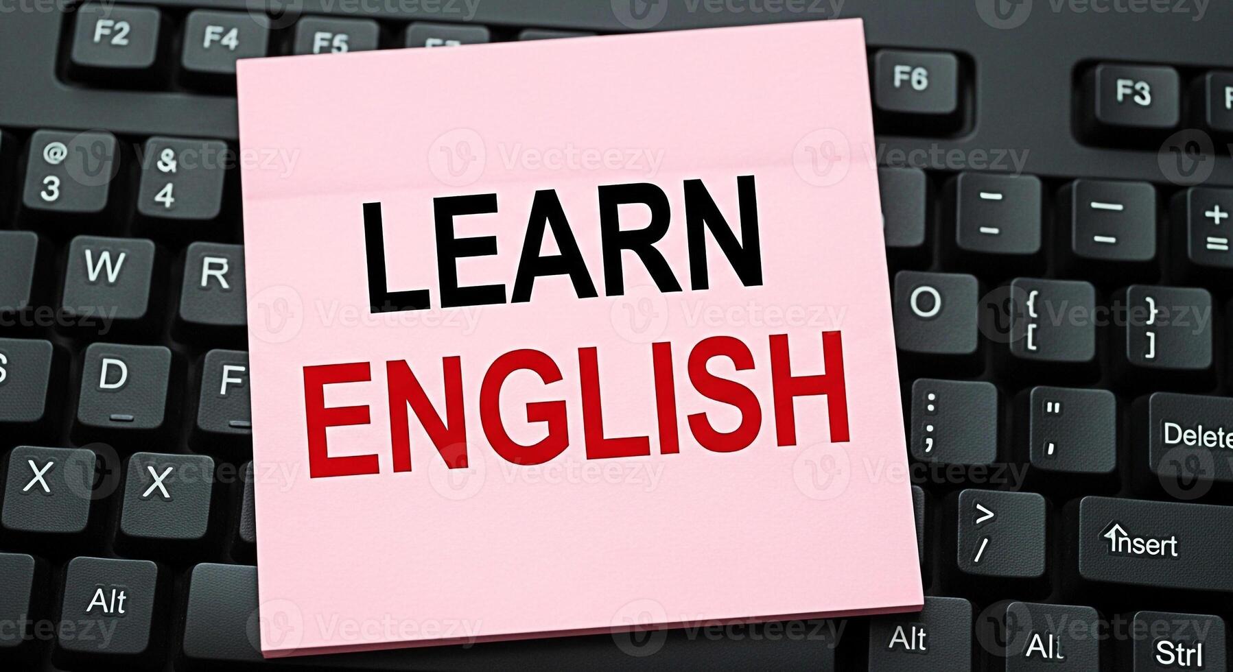 A pink sticky note with the words Learn English placed on a black computer keyboard symbolizing language acquisition and educational resources in a modern digital environment conveying a message of se photo