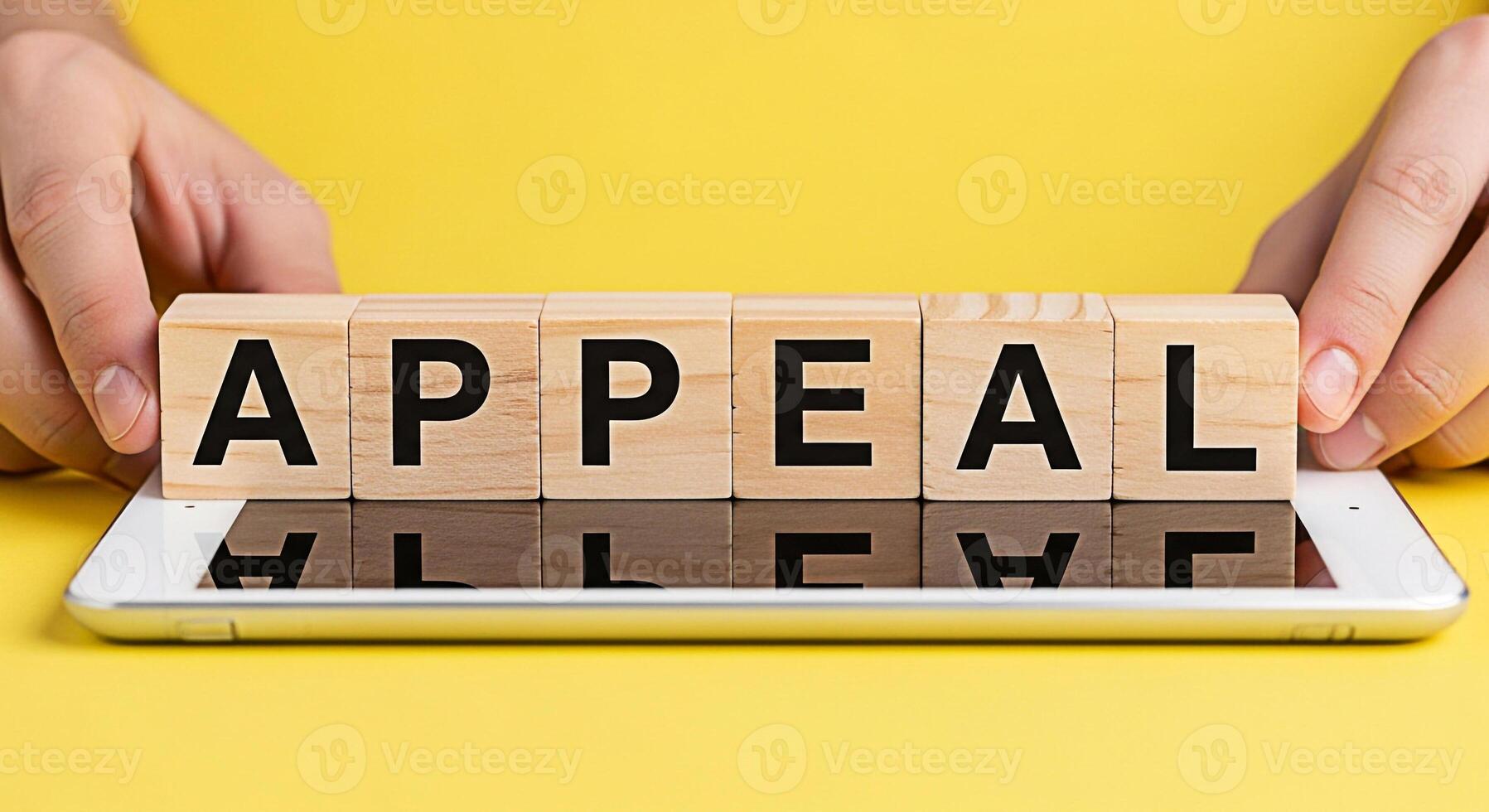 Closeup of hands arranging wooden blocks spelling APPEAL on a tablet against a vibrant yellow backdrop symbolizing legal recourse challenge and the process of seeking a review or change in a decision photo