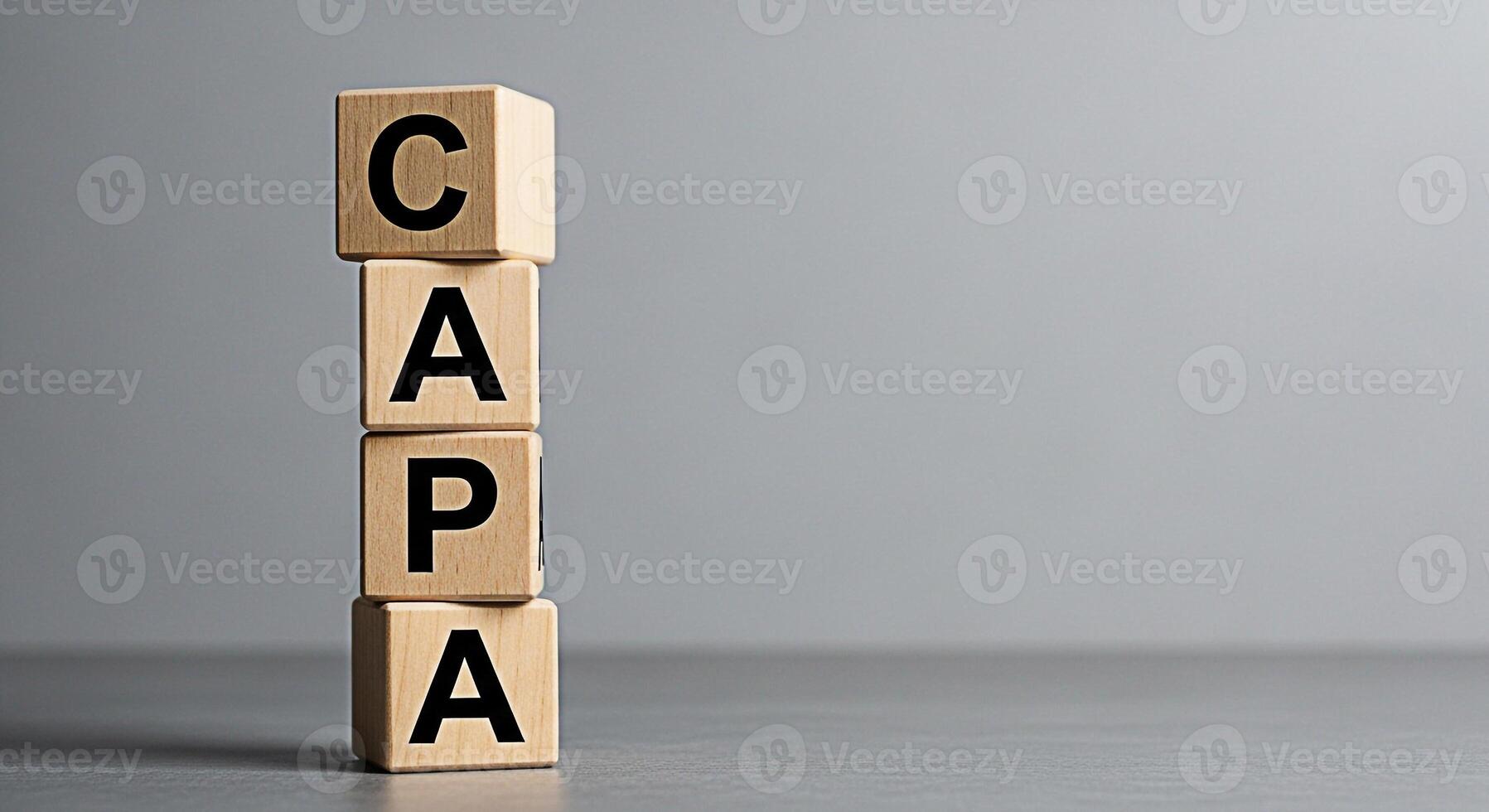 Wooden blocks displaying the acronym CAPA stacked on a gray surface representing Corrective and Preventive Action in a business setting promoting quality control and continuous improvement with a focu photo