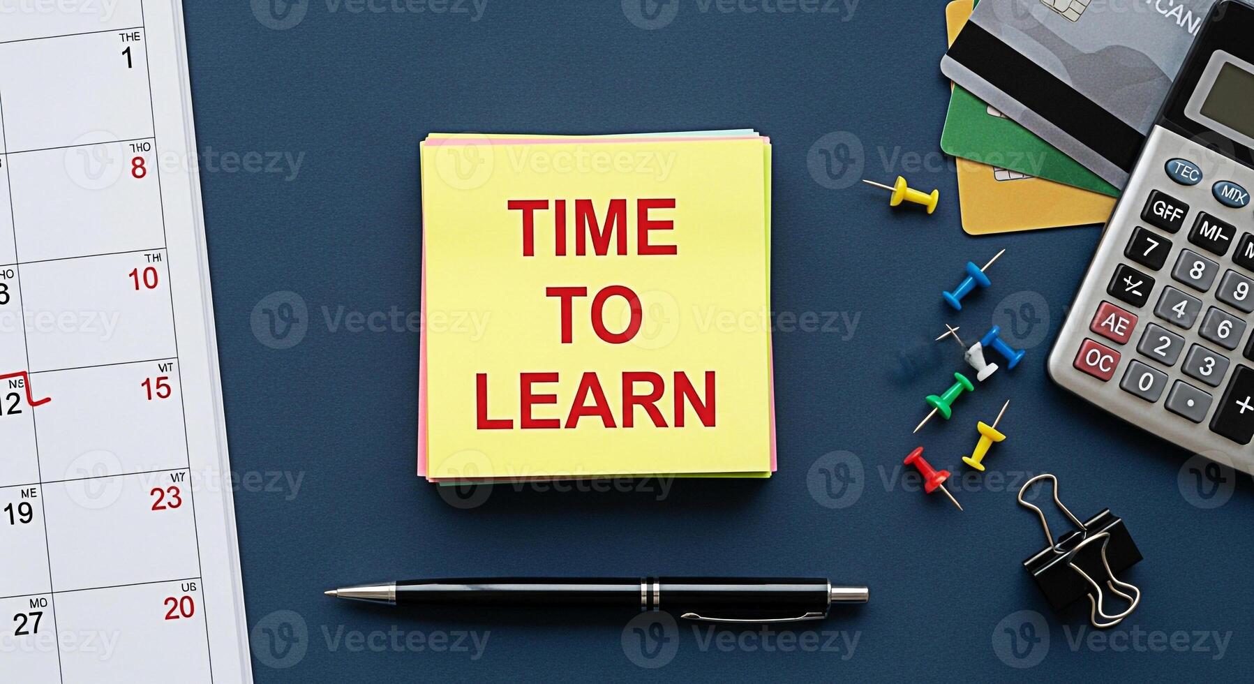 Overhead shot of a desk with a calendar calculator and sticky notes reminding its time to learn symbolizing education financial planning and scheduling on a dark blue background creating a focused and photo