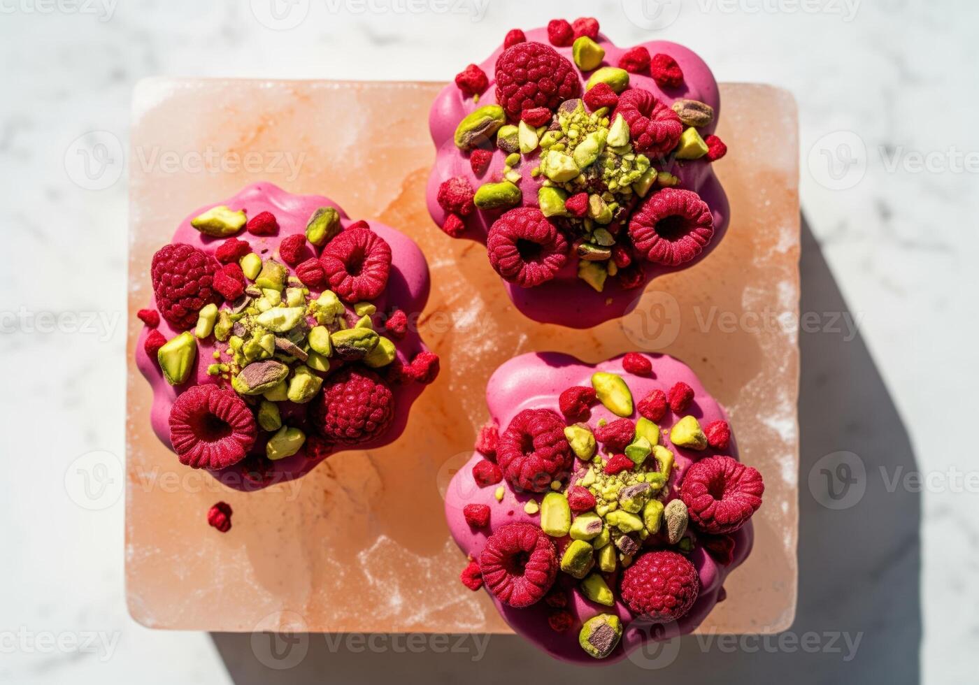Three gourmet ruby chocolate clusters topped with fresh raspberry and pistachio nuts. photo