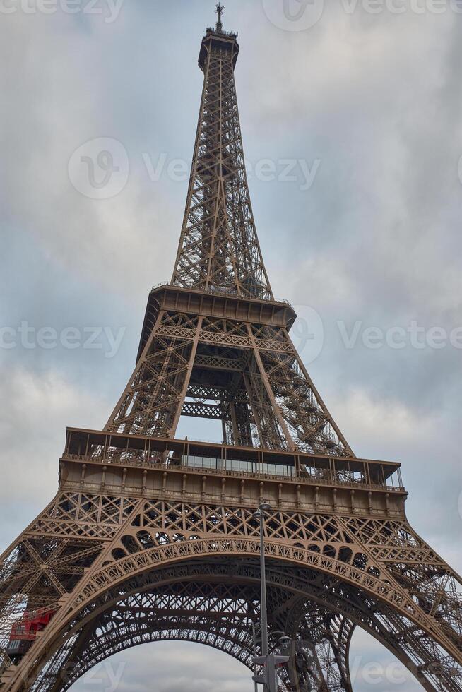 View of the Eiffel Tower in Paris, built for the 1889 World's Fair, with a cloudy sky and a metal structure photo