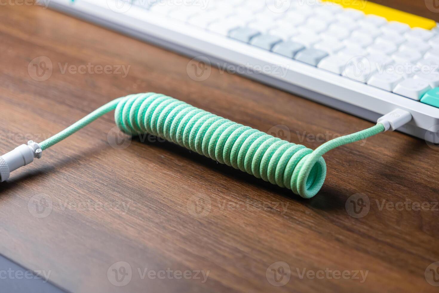 Mint green braided coiled USB-C cable connecting to a sleek white mechanical keyboard, emphasizing modern computing aesthetics and custom peripheral setups photo